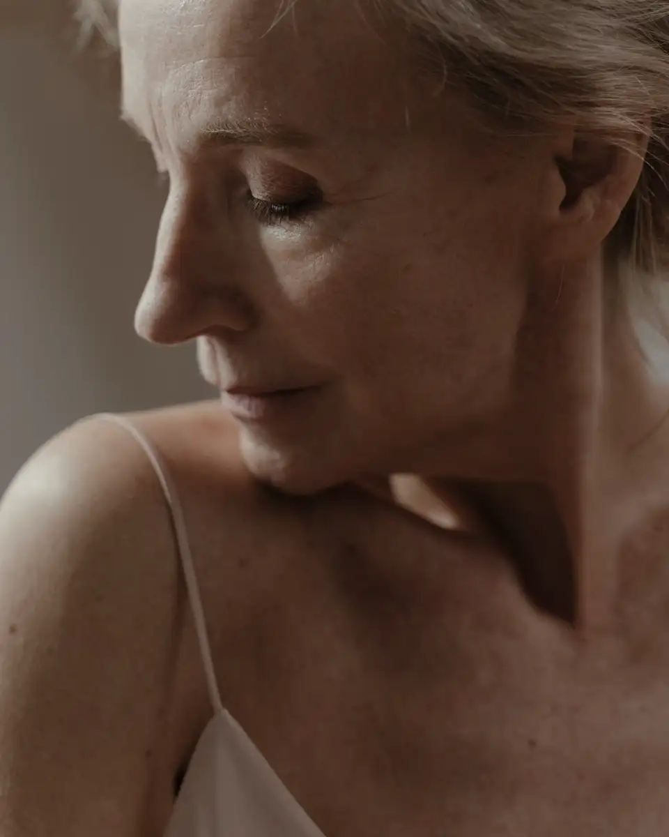 Close portrait of a mature woman with her eyes lowered, in soft side light