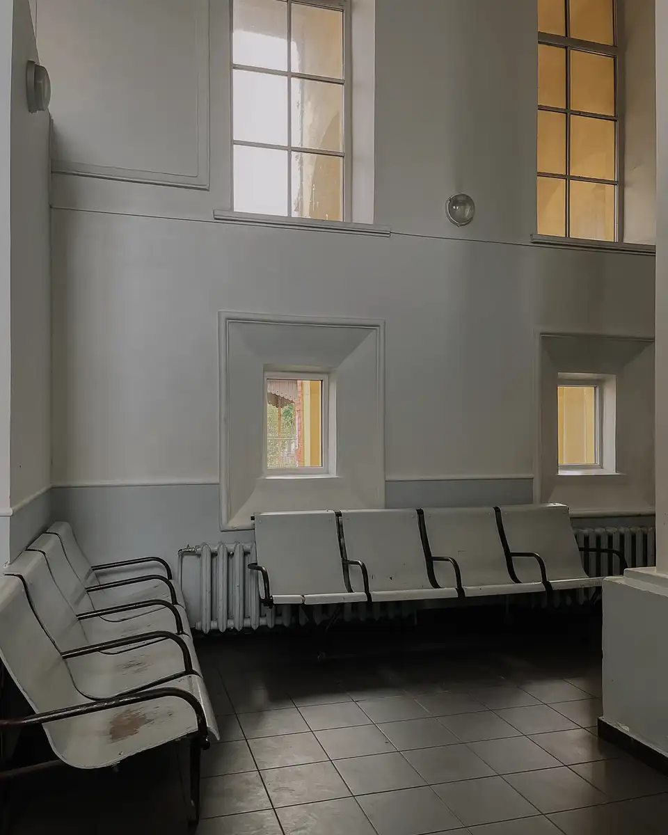 A quiet waiting room with chairs and tall windows letting in daylight